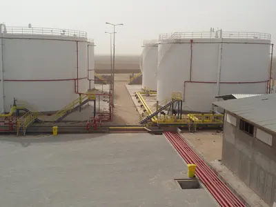 White steel storage tanks with yellow access stairs and piping, seen from above