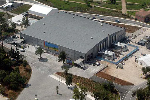 Aerial view of a large building with a grey roof, among trees
