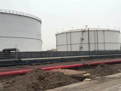White steel storage tanks behind ground-level piping