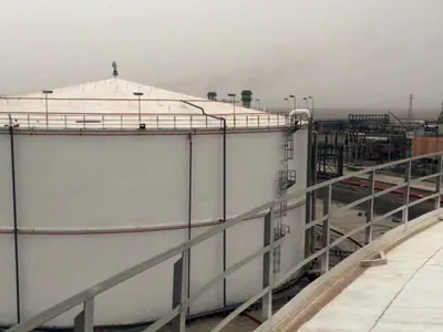 White storage tank with a fixed roof, seen from the top of another tank