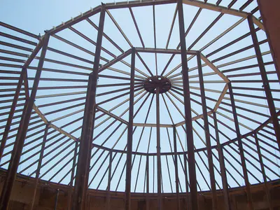 Radial steel roof frame of a tank, seen from inside against the sky