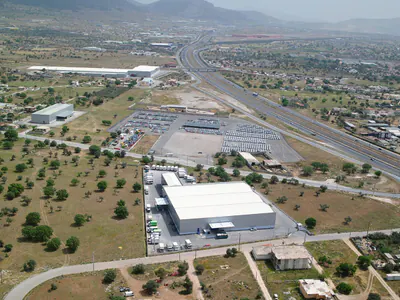 Warehouse near a motorway and a railway line, with a large car park beyond