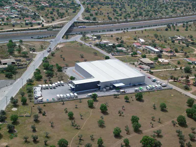Warehouse near a road bridge over a motorway, among fields and trees
