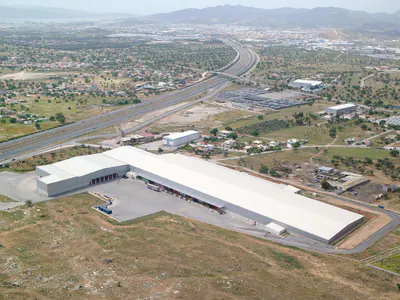 L-shaped warehouse with a long loading dock, motorway and hills behind