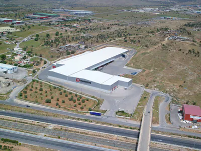 Logistics warehouse with loading docks, behind a planted grove and a motorway