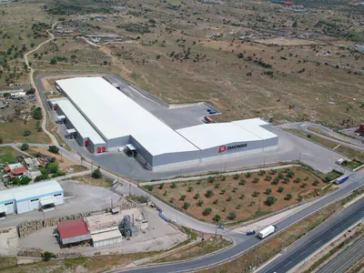 Long warehouse with a white roof and a row of loading doors, from above