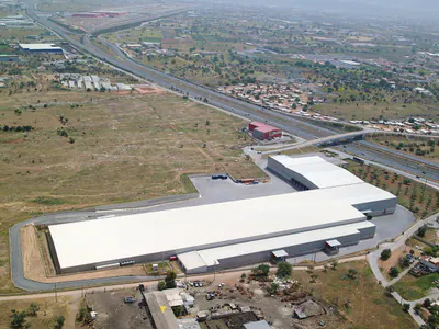 Wide warehouse roof beside a motorway, aerial view