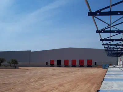 Loading doors along a warehouse facade, with the steel canopy frame overhead
