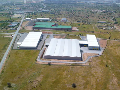 Warehouses with pitched white roofs and yellow loading doors, from above