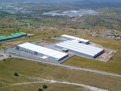Two long warehouses in open land, a green-roofed building nearby