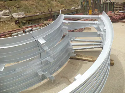 Curved galvanised steel ribs stacked in a fabrication yard