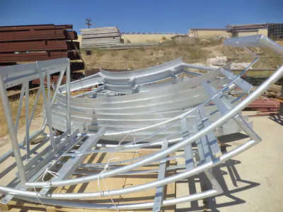 Curved galvanised steel frames stacked in a yard