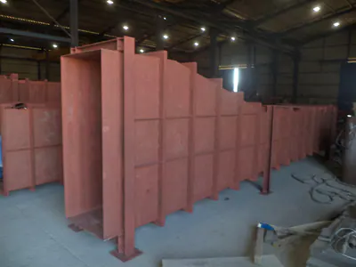 Tall red-primed duct sections standing in a workshop