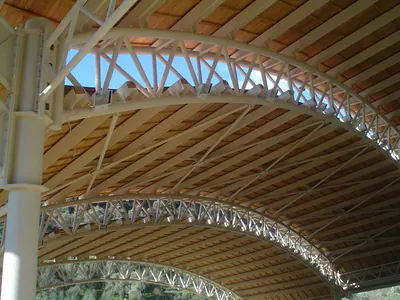 Underside of a curved shelter roof with white steel lattice trusses