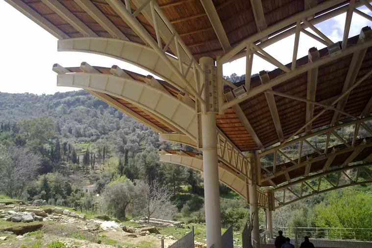 Shelter roof on round steel columns, with curved beams and lattice trusses, over an excavation