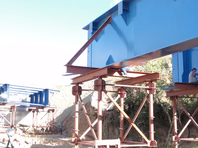 Blue bridge girder resting on temporary red steel supports