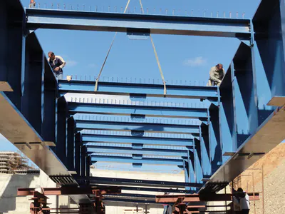 Cross beams between two blue bridge girders, seen from below