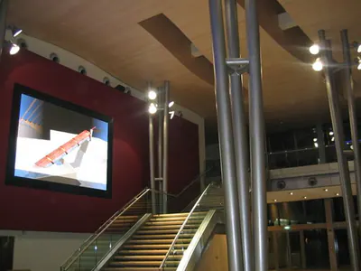 Interior with steel columns, a staircase and a large screen