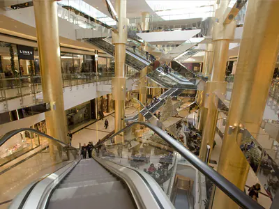 Multi-level shopping centre atrium with escalators and gold-coloured columns