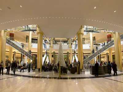 Wide view of a shopping centre court with escalators and visitors
