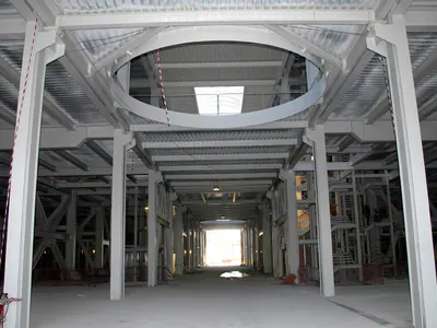 Bare steel frame of a building interior with a circular opening in the upper floor