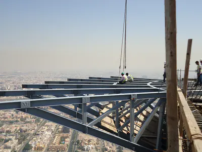 Steel frame cantilevering from a tower top, the city far below
