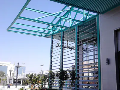 Teal steel canopy frame and horizontal louvres at a building corner