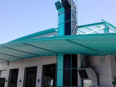Workshop entrance with a curved teal canopy and a tall duct