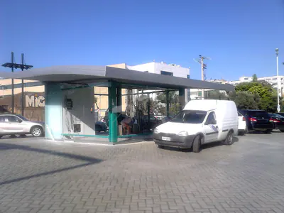 Low glazed pavilion with a flat canopy and parked vehicles