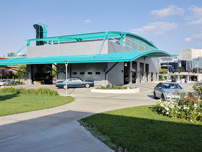Workshop building with a long curved teal canopy beside lawns