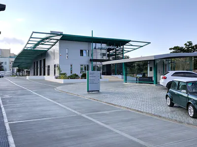 Forecourt with parked cars in front of a building with teal steel canopies