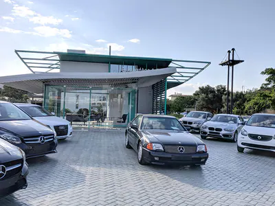 Glazed pavilion with a cantilevered canopy and cars on the forecourt