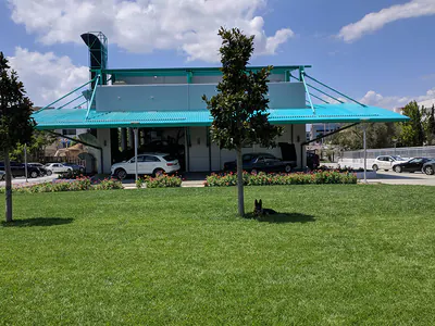 Building with a teal canopy, seen across a lawn with trees