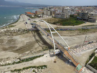 Arch bridge at a river mouth by the sea, with the town behind
