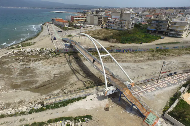 Arch bridge at a river mouth by the sea, with the town behind