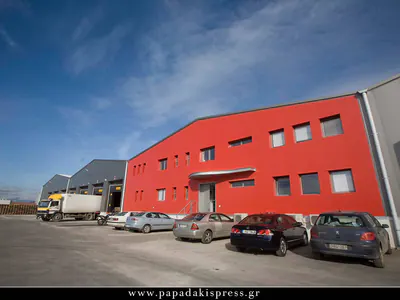 Red-clad office block attached to a warehouse, cars parked in front