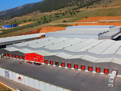 Long warehouse with red loading doors beside a boundary wall