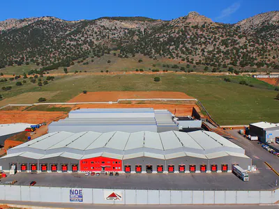 Warehouse with red loading doors below rocky mountains