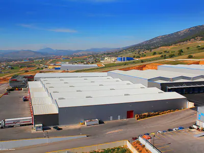 Large warehouse with multiple pitched roofs and a truck, aerial view