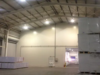 Warehouse hall with stacked pallets and an opening into a second hall
