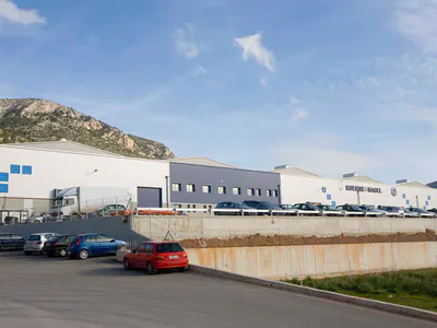 Warehouse and office buildings with a car park, hills behind