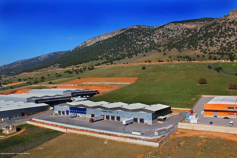 Warehouses beside open fields at the foot of a mountain