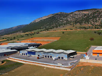 Warehouses beside open fields at the foot of a mountain