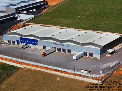 Warehouse with multiple pitched roofs and loading docks, aerial view with a caption in the corner