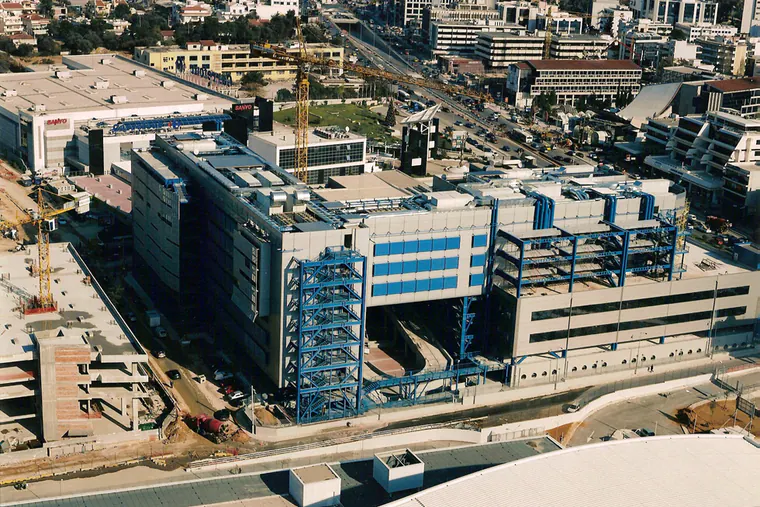 Multi-storey building with blue steel stair towers and blue steel frames, aerial view, construction works around it