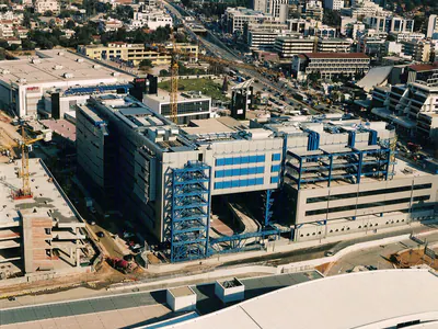 Multi-storey building with blue steel stair towers and blue steel frames, aerial view, construction works around it