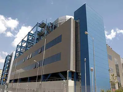 Building facade with a tall blue-clad tower and a blue external steel frame