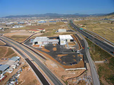 Warehouse and office complex between a railway line and a motorway, aerial view
