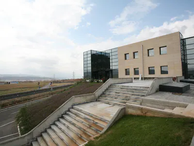 Stone-clad office block with glazed corners above wide outdoor steps