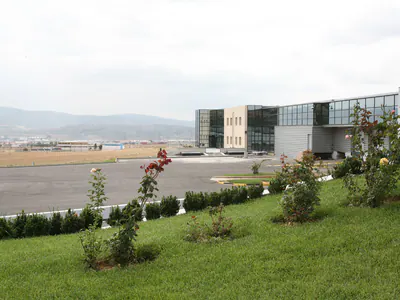 Office building beyond a lawn with rose bushes and low shrubs